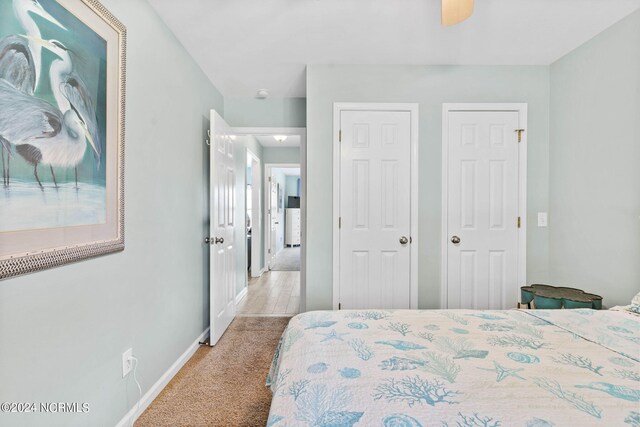 carpeted bedroom with ceiling fan and multiple closets