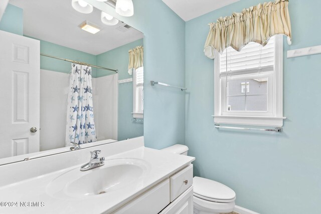 bathroom featuring a shower with shower curtain, vanity, and toilet