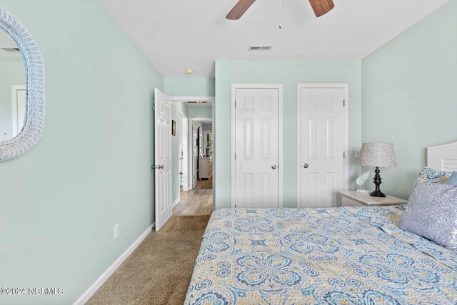 bedroom with multiple closets, ceiling fan, and carpet floors