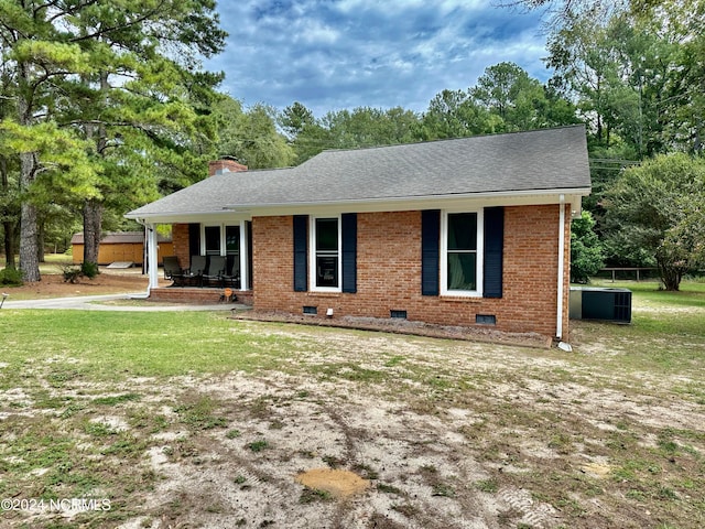 ranch-style home with central air condition unit and a front lawn