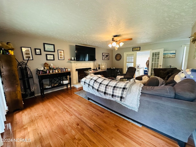 bedroom with light hardwood / wood-style floors, a textured ceiling, and ceiling fan