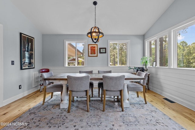 dining room with lofted ceiling, an inviting chandelier, and light hardwood / wood-style flooring