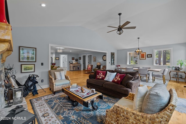 living room with lofted ceiling, hardwood / wood-style flooring, and ceiling fan with notable chandelier