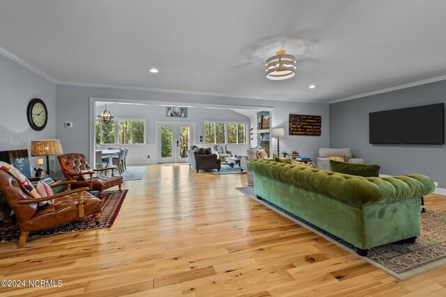 living room with french doors, crown molding, a chandelier, and light hardwood / wood-style flooring