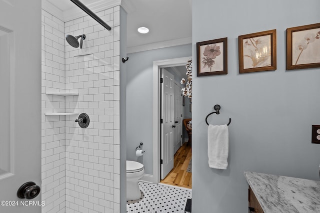 bathroom featuring crown molding, tiled shower, vanity, and toilet