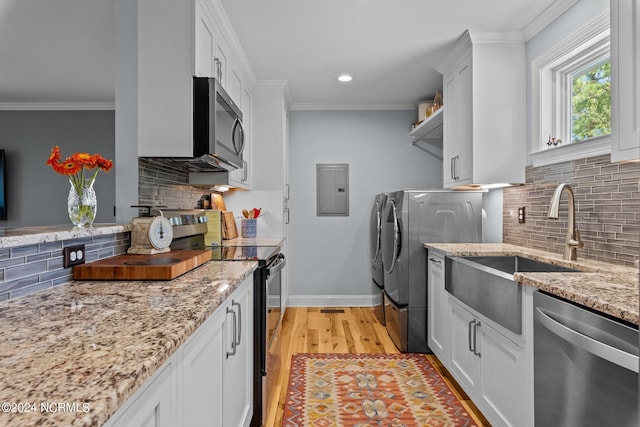 kitchen featuring crown molding, appliances with stainless steel finishes, light stone counters, washer and dryer, and white cabinets