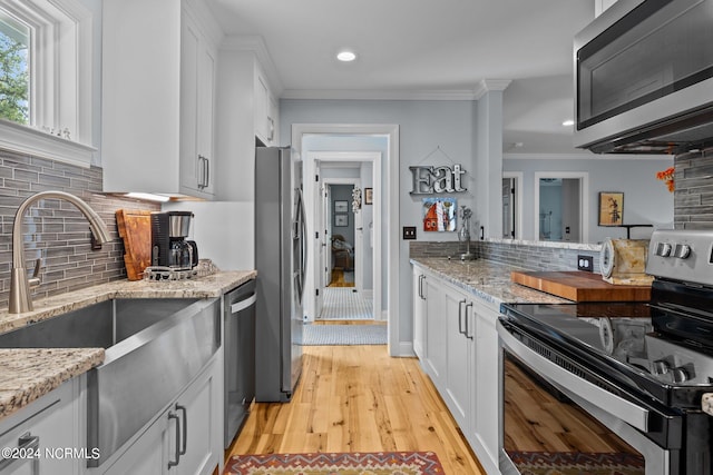 kitchen featuring crown molding, light stone countertops, white cabinets, and appliances with stainless steel finishes