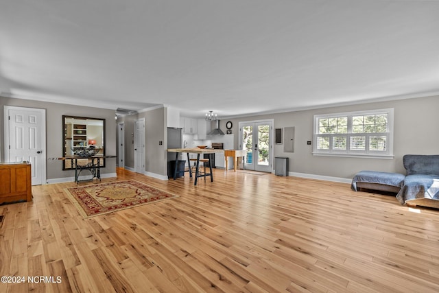 living room with french doors, ornamental molding, and light wood-type flooring