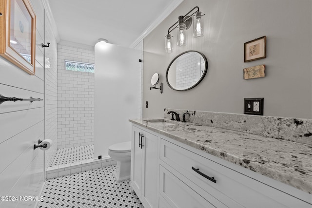 bathroom with vanity, crown molding, toilet, and a tile shower