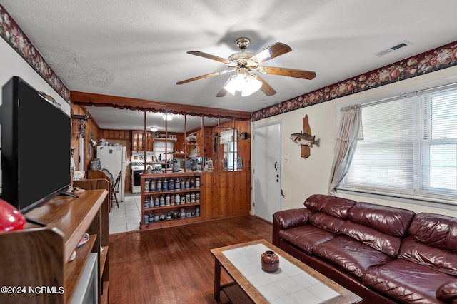 living room featuring dark wood-type flooring, ceiling fan, and a textured ceiling