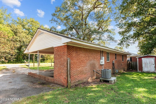 view of side of home featuring a storage unit, a lawn, a carport, and cooling unit