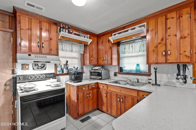 kitchen featuring plenty of natural light, light tile patterned floors, white range with electric cooktop, and sink