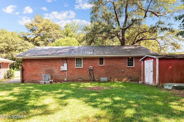 rear view of house featuring a yard, central AC, and a shed