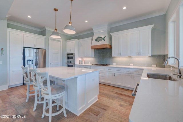 kitchen with a center island, light hardwood / wood-style flooring, stainless steel appliances, white cabinetry, and sink