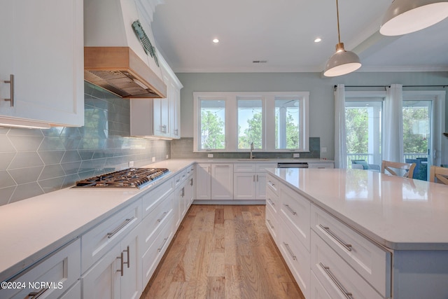 kitchen with pendant lighting, stainless steel gas cooktop, white cabinetry, custom exhaust hood, and light wood-type flooring