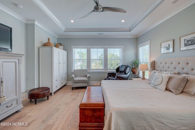 bedroom featuring light hardwood / wood-style flooring, ceiling fan, ornamental molding, and a tray ceiling