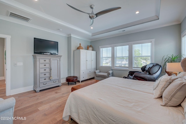 bedroom with ceiling fan, a raised ceiling, crown molding, and light hardwood / wood-style flooring