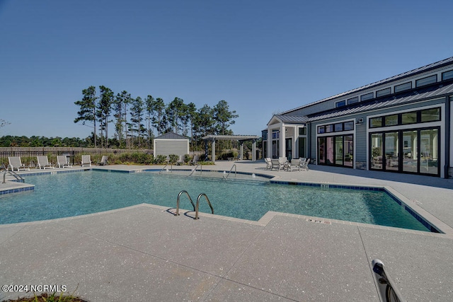 view of pool featuring a patio area and a storage shed