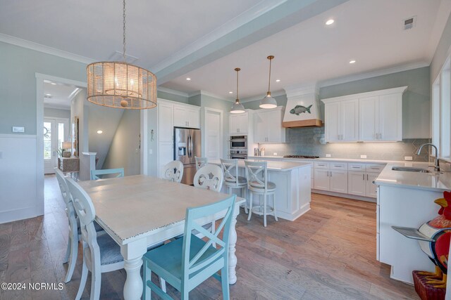 dining space featuring crown molding, light hardwood / wood-style flooring, sink, and a chandelier