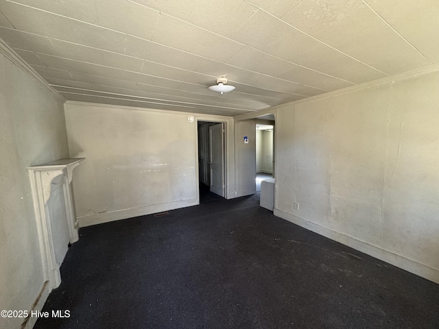 unfurnished room featuring baseboards and dark carpet