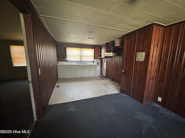 kitchen featuring a sink, electric water heater, and wooden walls