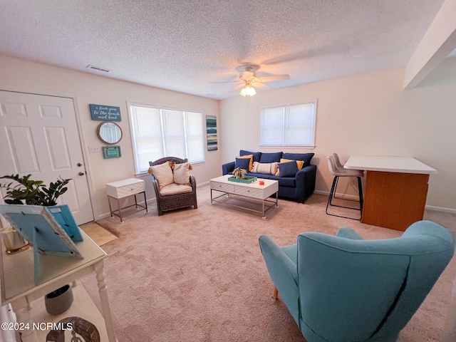 carpeted living room with a textured ceiling, plenty of natural light, and ceiling fan