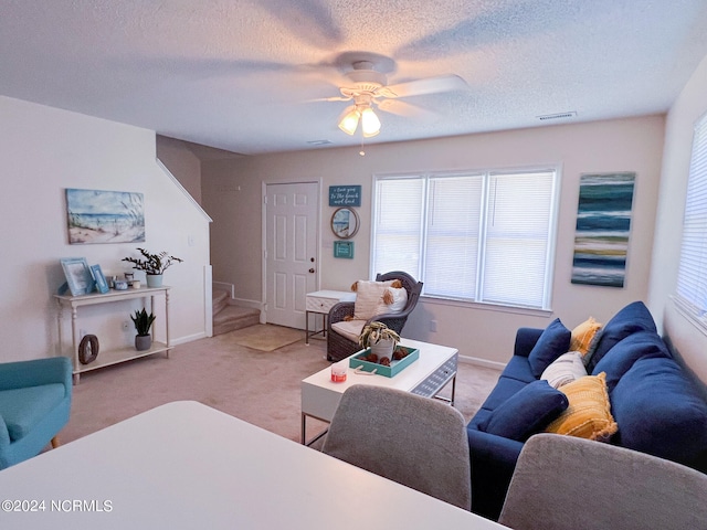 living room featuring a textured ceiling, ceiling fan, and carpet