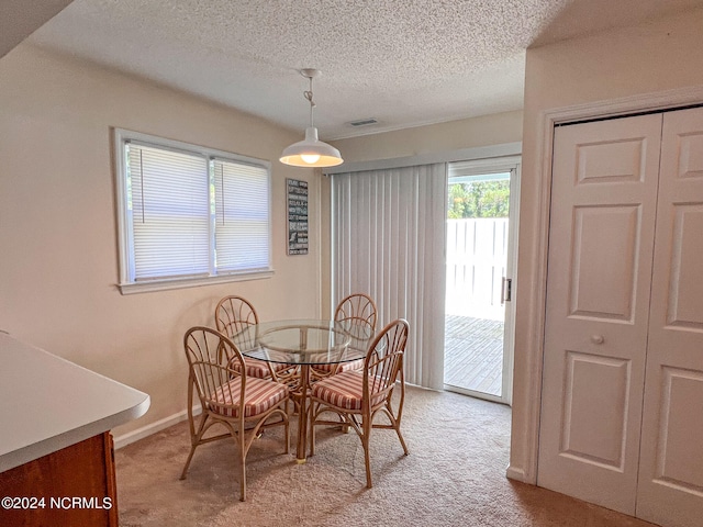 dining room with light carpet and a textured ceiling