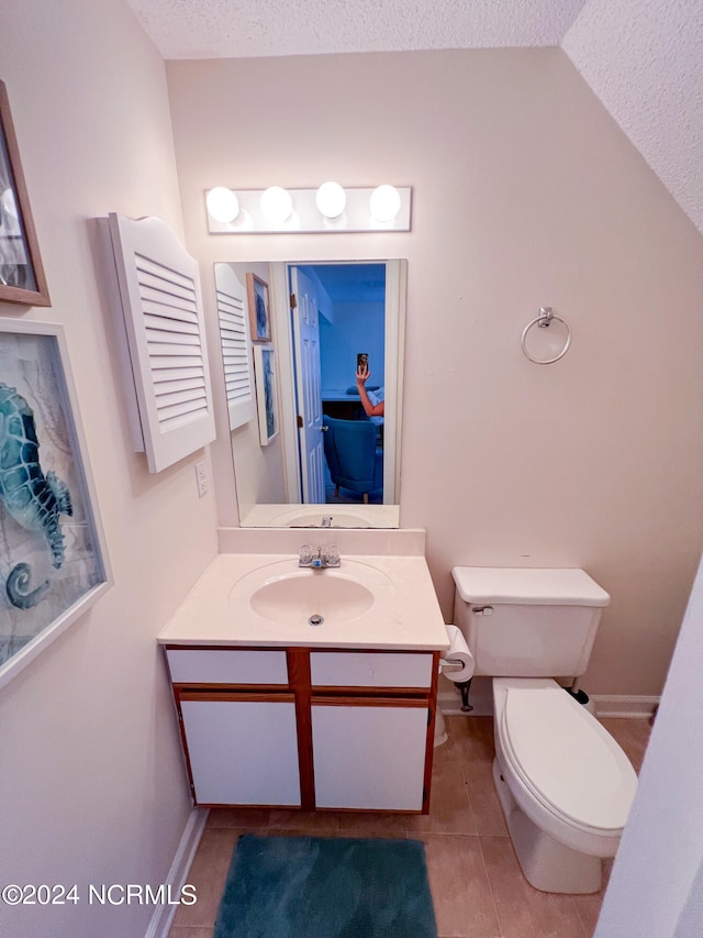 bathroom featuring a textured ceiling, vanity, tile patterned flooring, toilet, and lofted ceiling