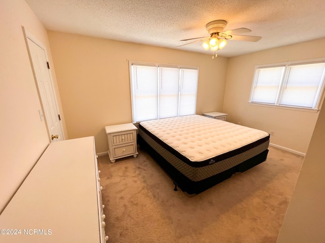 bedroom featuring a textured ceiling, light colored carpet, and ceiling fan