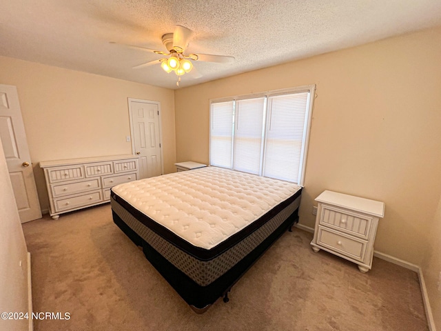 carpeted bedroom featuring ceiling fan and a textured ceiling