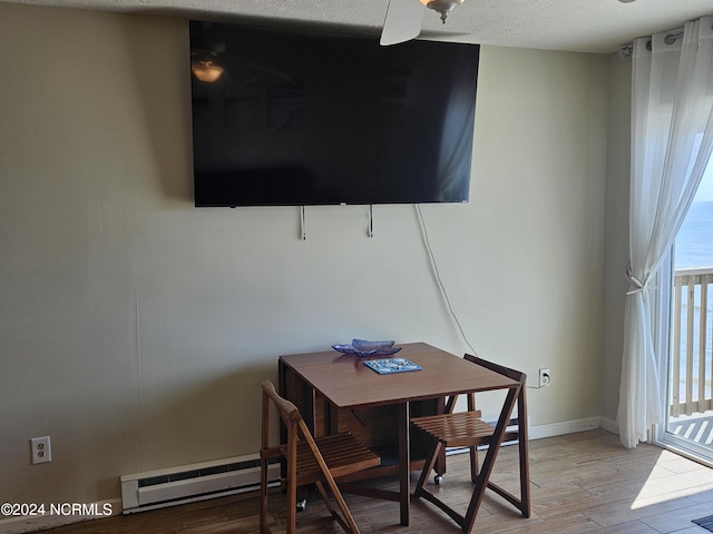 dining room featuring ceiling fan, light wood-type flooring, a textured ceiling, and a baseboard heating unit