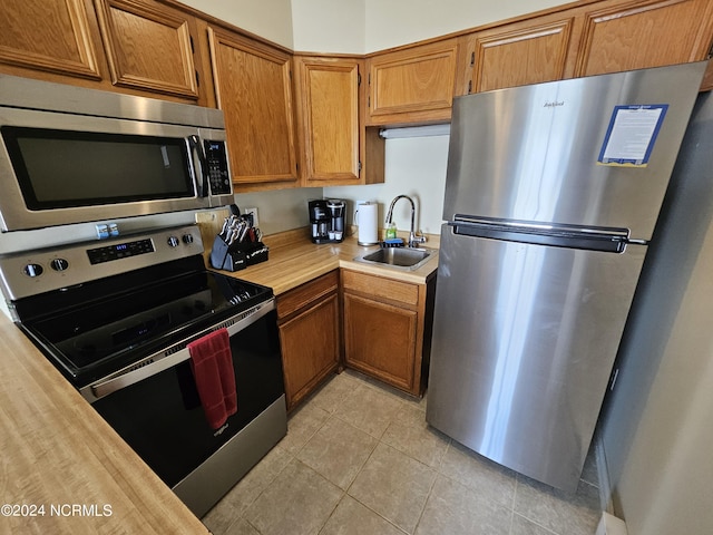 kitchen featuring sink, light tile patterned floors, and stainless steel appliances