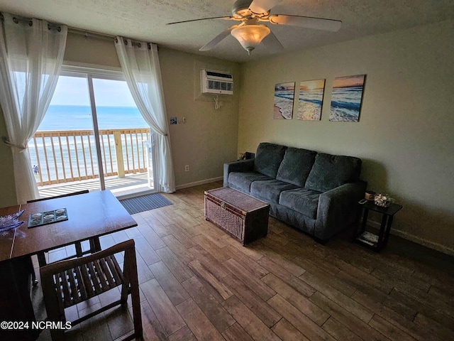 living room with hardwood / wood-style flooring, ceiling fan, a wall mounted AC, a water view, and a textured ceiling