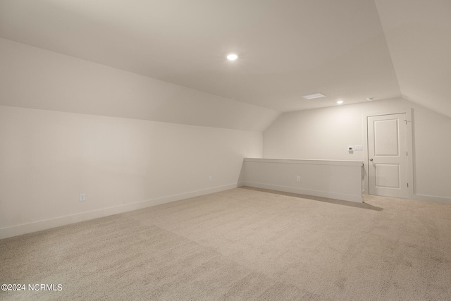 additional living space with vaulted ceiling and light colored carpet