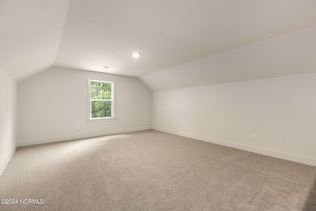 additional living space featuring lofted ceiling and carpet flooring