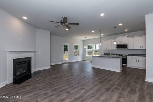 kitchen featuring appliances with stainless steel finishes, light stone counters, sink, white cabinets, and hanging light fixtures