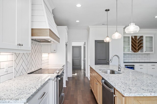 kitchen featuring sink, stainless steel appliances, premium range hood, an island with sink, and white cabinets