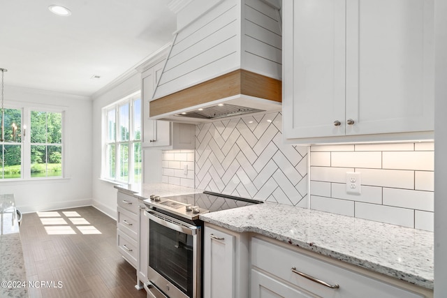 kitchen featuring white cabinetry, light stone counters, stainless steel electric stove, decorative backsplash, and custom range hood