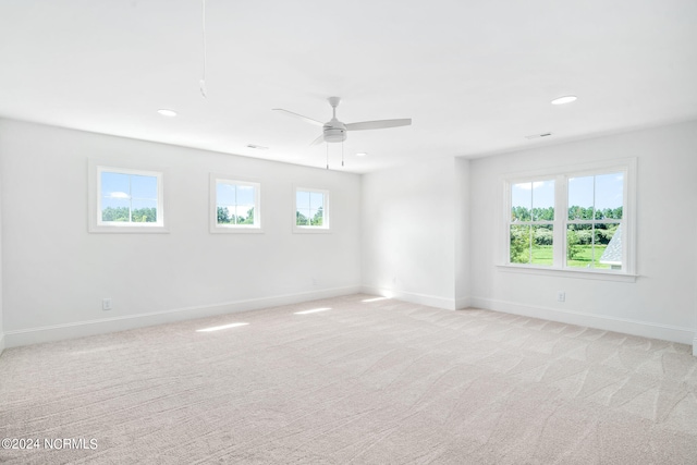 carpeted empty room with ceiling fan and a wealth of natural light