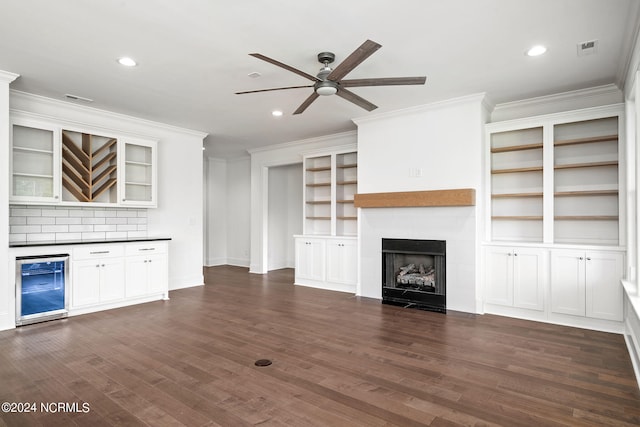 unfurnished living room featuring ornamental molding, dark wood-type flooring, beverage cooler, and a tiled fireplace