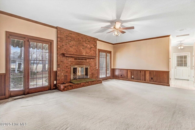 unfurnished living room featuring ornamental molding, a fireplace, light colored carpet, and ceiling fan