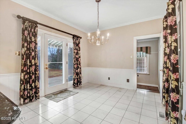 unfurnished dining area with ornamental molding, light tile patterned flooring, and an inviting chandelier