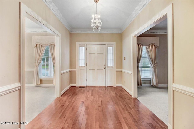 entrance foyer featuring an inviting chandelier, crown molding, and light hardwood / wood-style floors