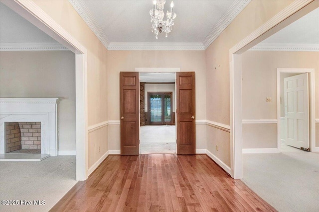 corridor featuring an inviting chandelier, ornamental molding, and light hardwood / wood-style floors