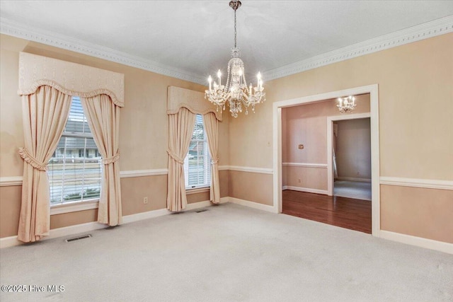 spare room with crown molding, carpet flooring, and a notable chandelier