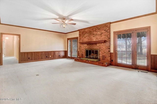 unfurnished living room featuring crown molding, a brick fireplace, carpet floors, and wooden walls