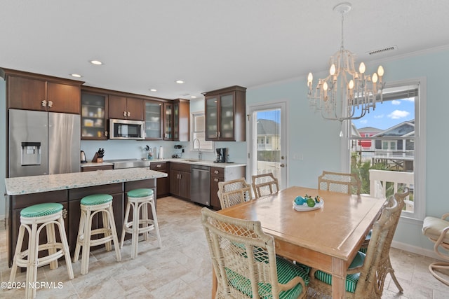 dining space with a chandelier, crown molding, and sink