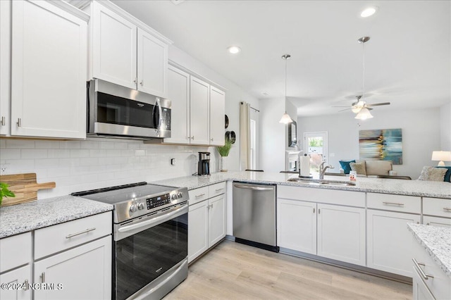 kitchen with white cabinets, appliances with stainless steel finishes, light hardwood / wood-style floors, ceiling fan, and pendant lighting