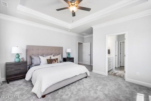 carpeted bedroom featuring ceiling fan, ensuite bathroom, a raised ceiling, and ornamental molding